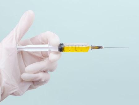 Picture of a gloved hand holding a syringe
